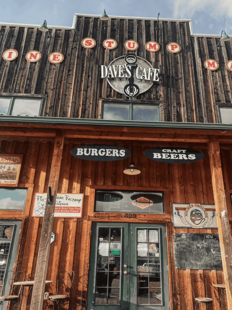 Rustic restaurant facade with "Dave's Cafe" sign, offering burgers and craft beers, inviting outdoor seating.