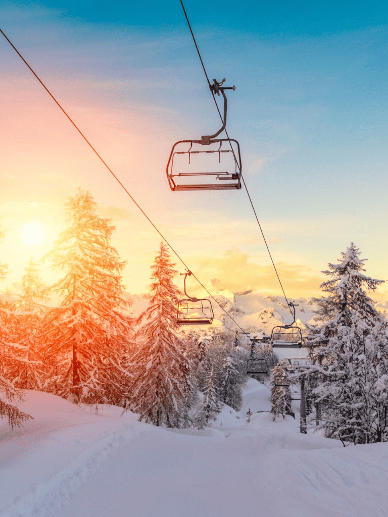Enjoy winter skiing with scenic snowy mountain views and chairlift rides during sunset.
