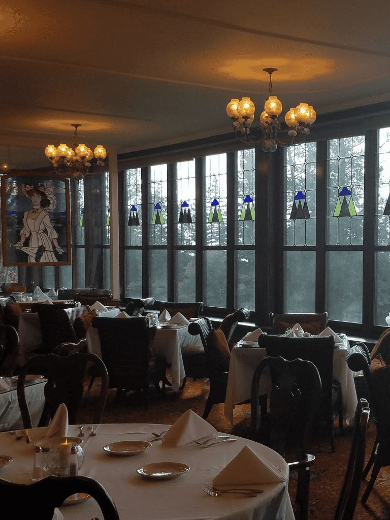 Elegant restaurant interior with large stained glass windows and vintage chandeliers for a refined dining experience.