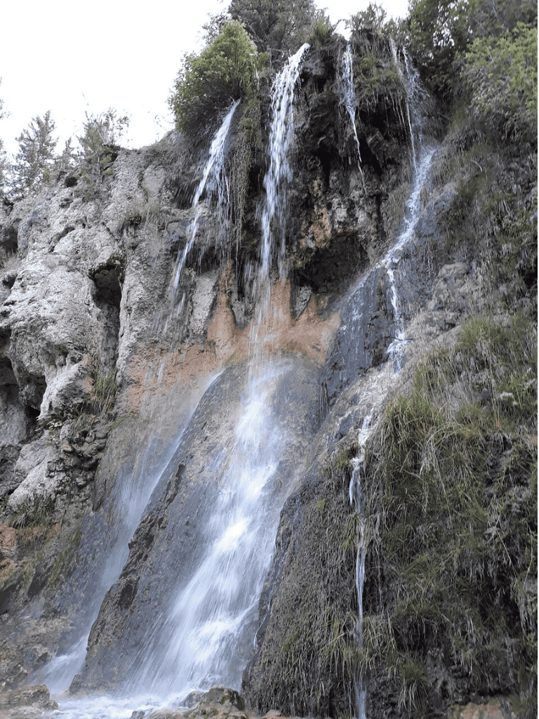 Gorgeous cascading waterfall on rugged mountain rocks with lush greenery.