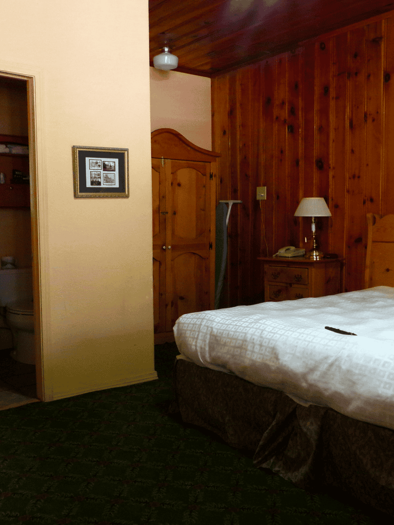 Old-fashioned bedroom with wood-paneled walls and cozy decor, ideal for a rustic getaway at Quest for Directions.