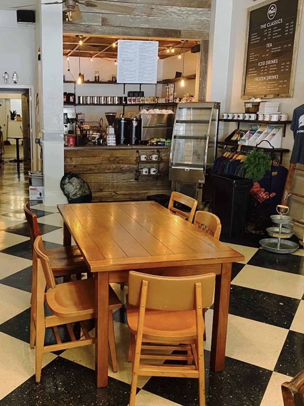 Cozy café interior with wooden dining table and checkered flooring, featuring a serving counter and menu board at QuestForDirections.