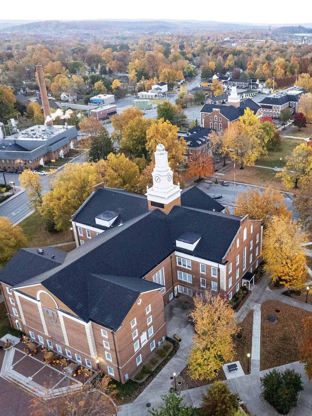 Aerial view of a historic town square with autumn foliage, featuring a classic courthouse or government building.