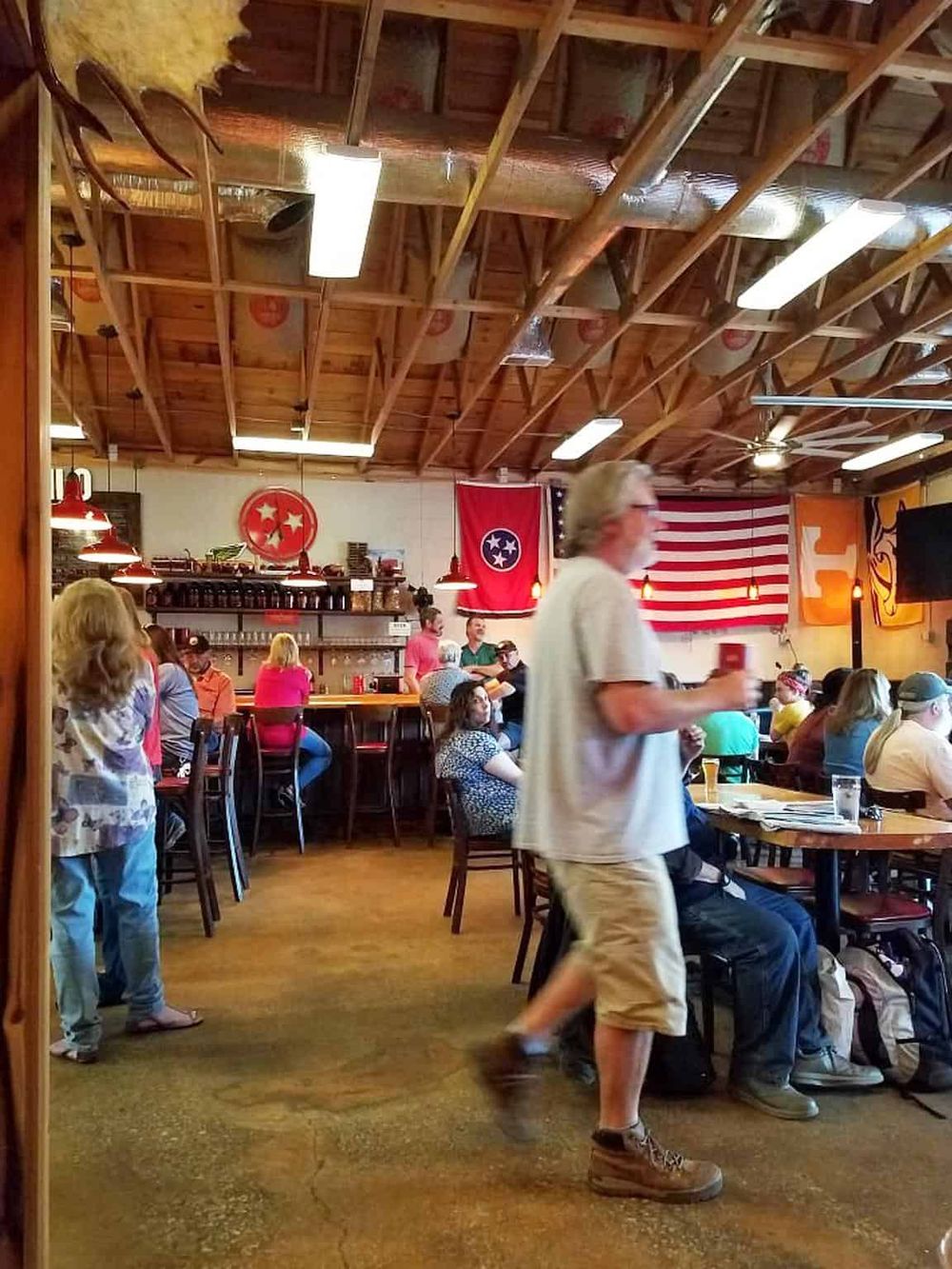 Enjoying sports bar atmosphere with fans and Memphis Tigers flags, perfect for Tennessee sports fans and live game viewing.