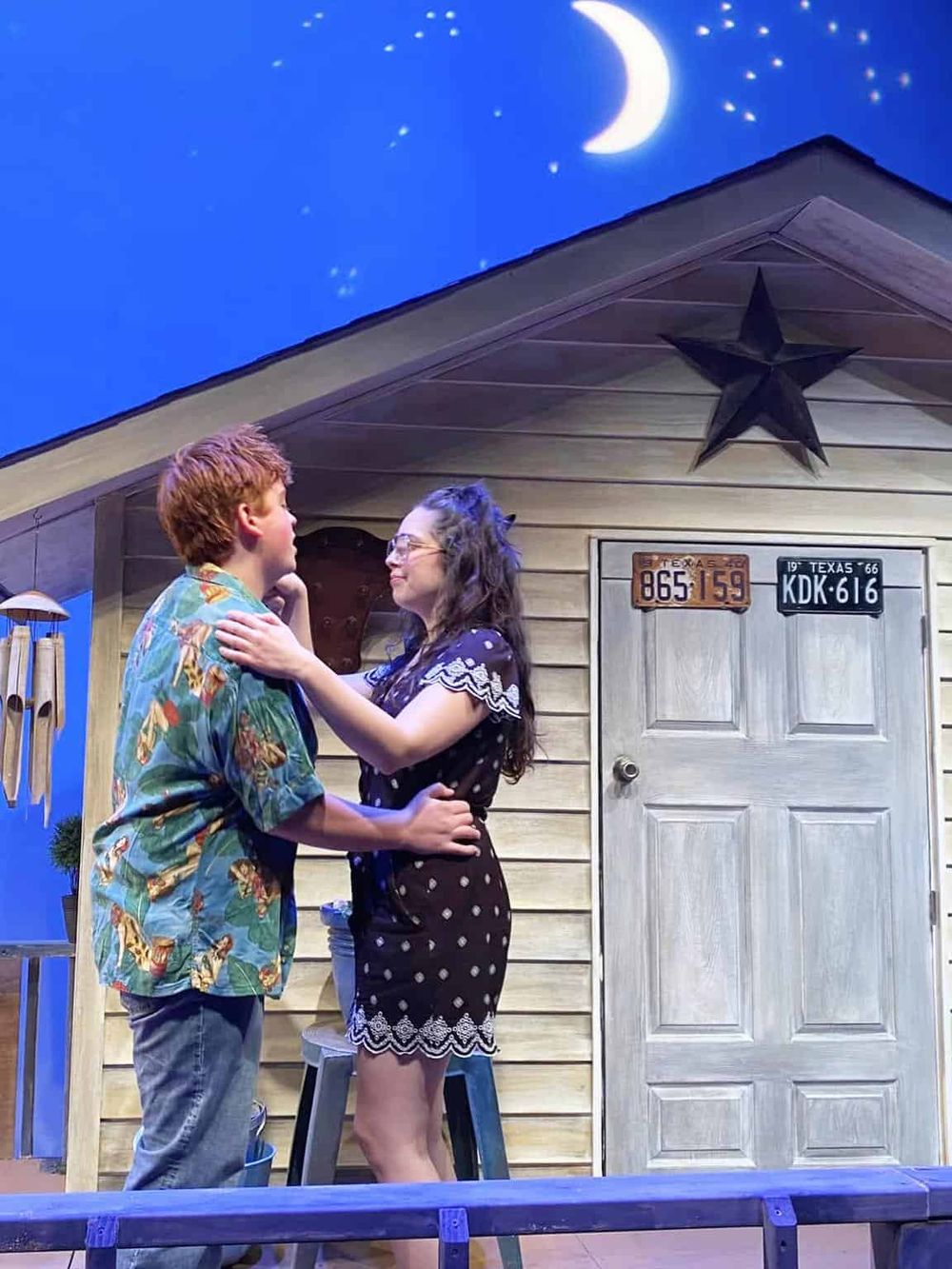 1. Romantic couple embracing in cozy rustic house with star decor under moonlit sky.