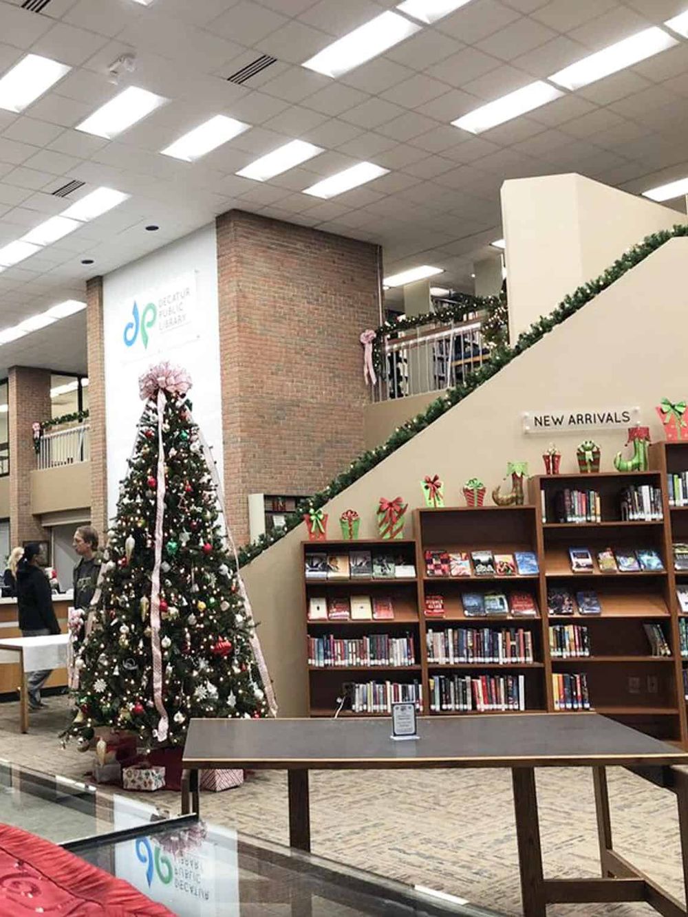 Decorative Christmas tree at a public library during the holiday season, festive atmosphere with books and holiday decor.