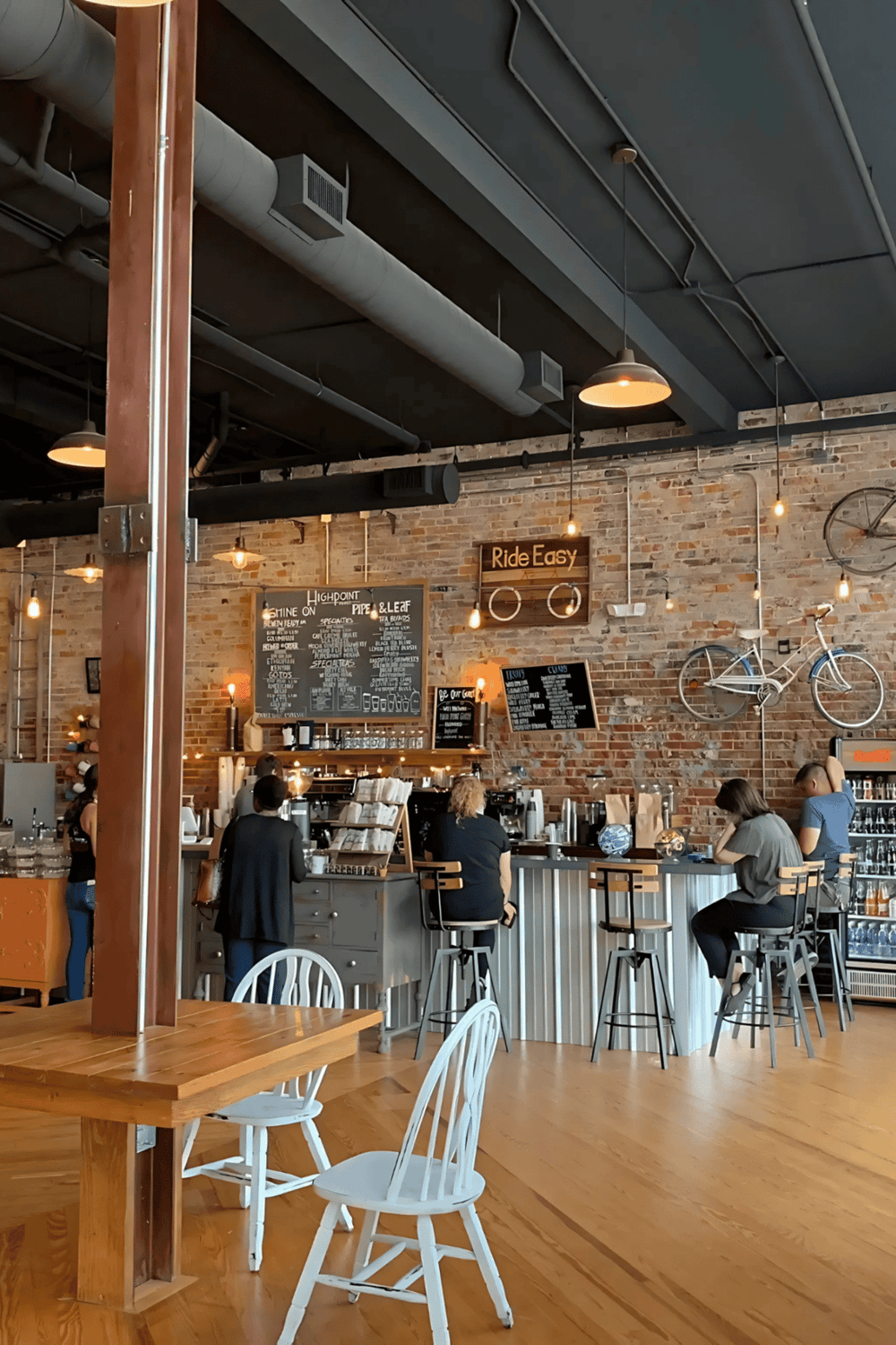 Cozy coffee shop with brick walls, modern decor, and customers enjoying their drinks.