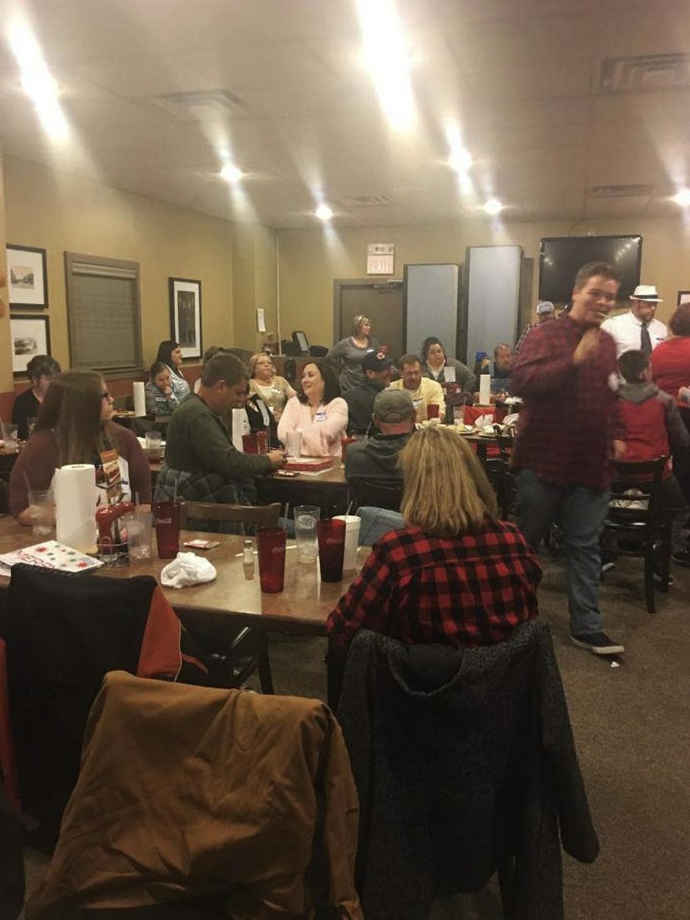 A lively, social gathering at a cozy restaurant with people enjoying meals and conversations.