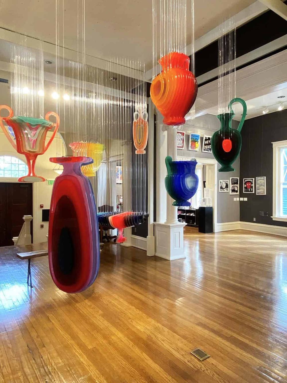 Colorful Murano glass vases and sculptures display artistic craftsmanship in an indoor gallery.