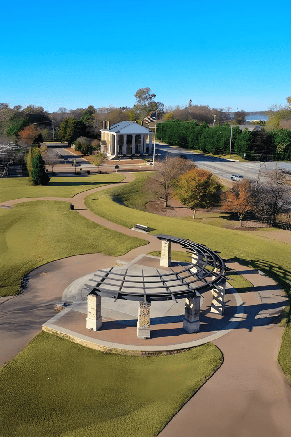 View of a park and historic building with QuestForDirections signage, outdoor sculpture, and scenic landscape.