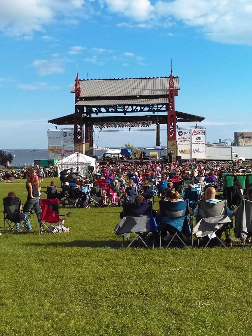Open-air concert at QuestForDirections with a large crowd enjoying live music by the waterfront.