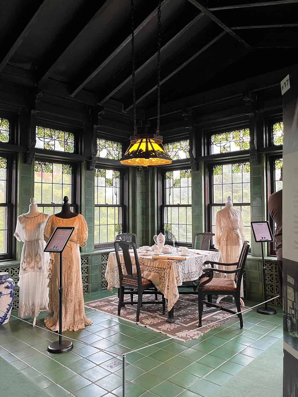 Vintage Victorian dining room with green tiled walls and decorative windows.