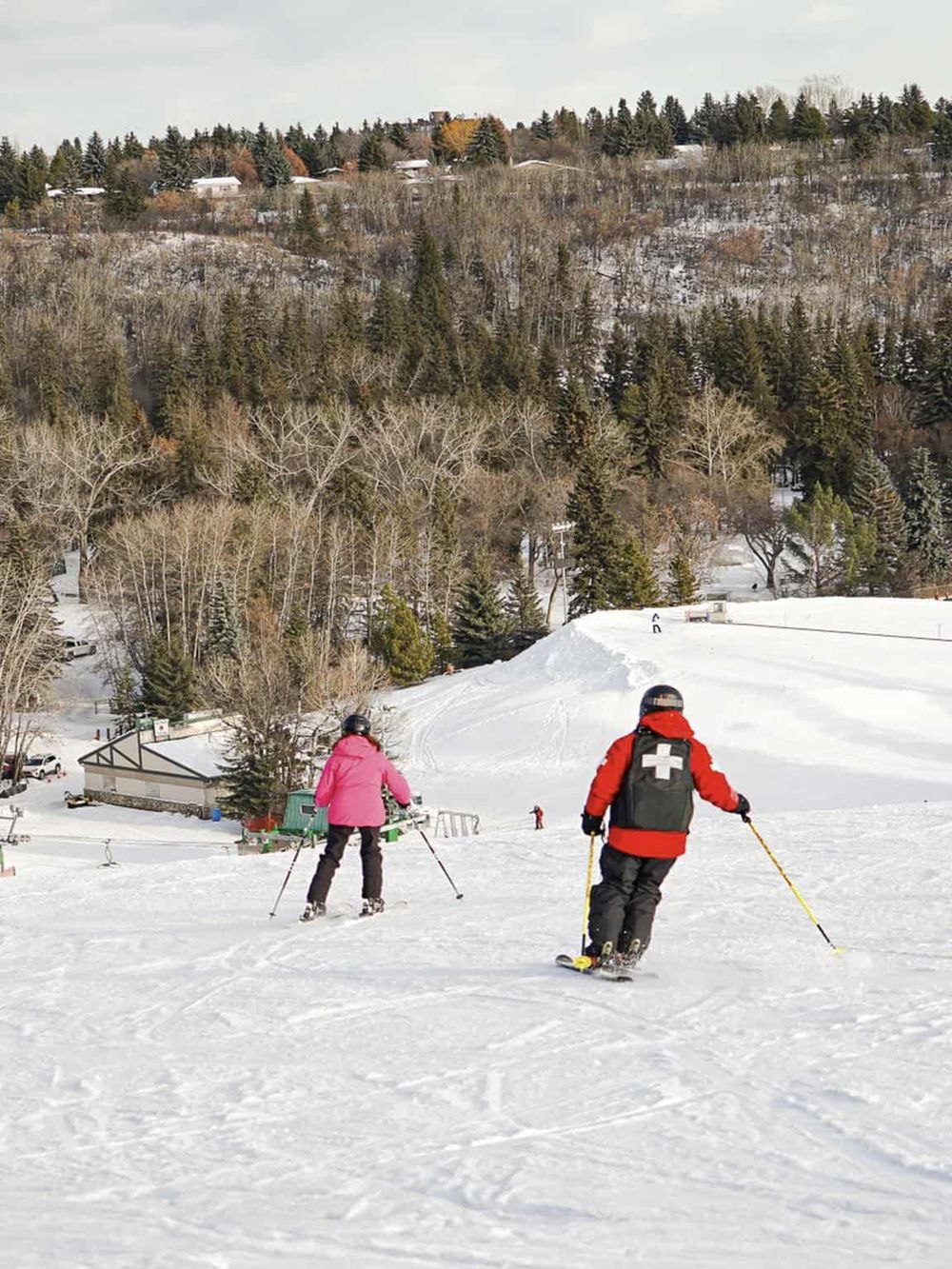 Skier in red jacket with medical cross on back on snowy mountain slope at QuestForDirections.