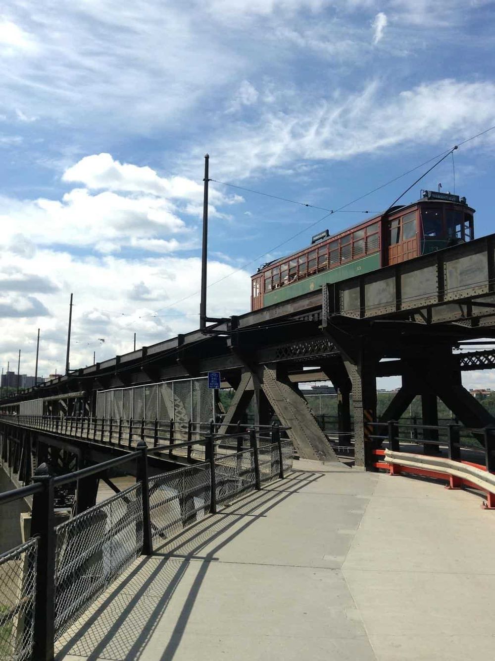 Vintage streetcar on elevated railway tracks in an urban area.