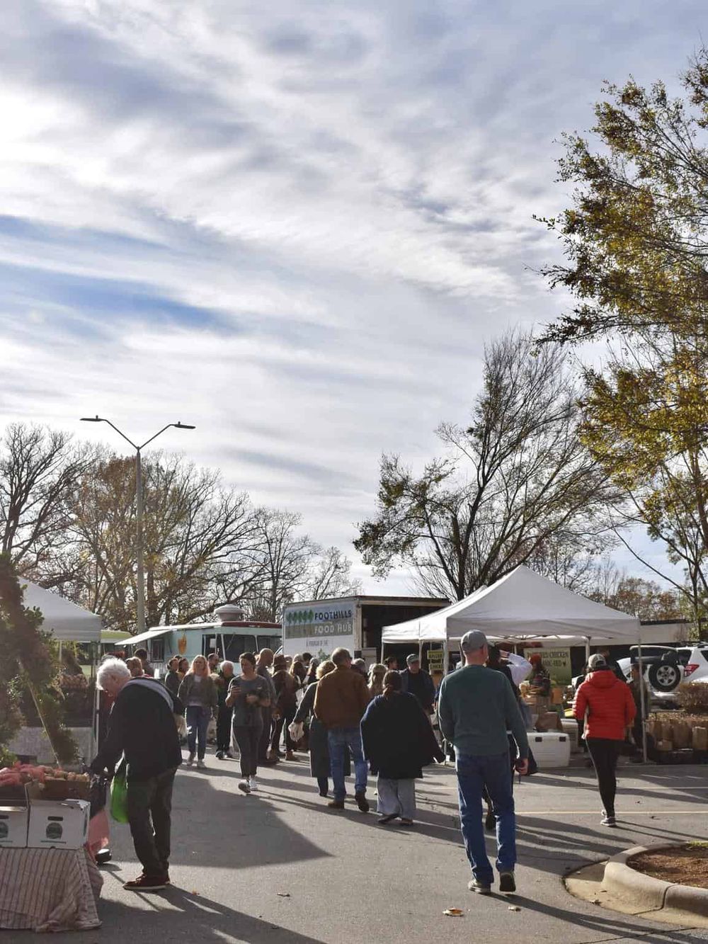 Fresh farmers market at Foothills Food Hub with people shopping outdoors on a sunny day.