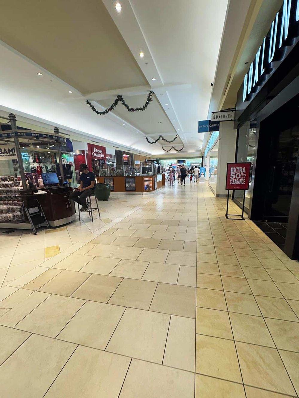 Bright shopping mall corridor with stores and shoppers, QuestForDirections affiliate branding.