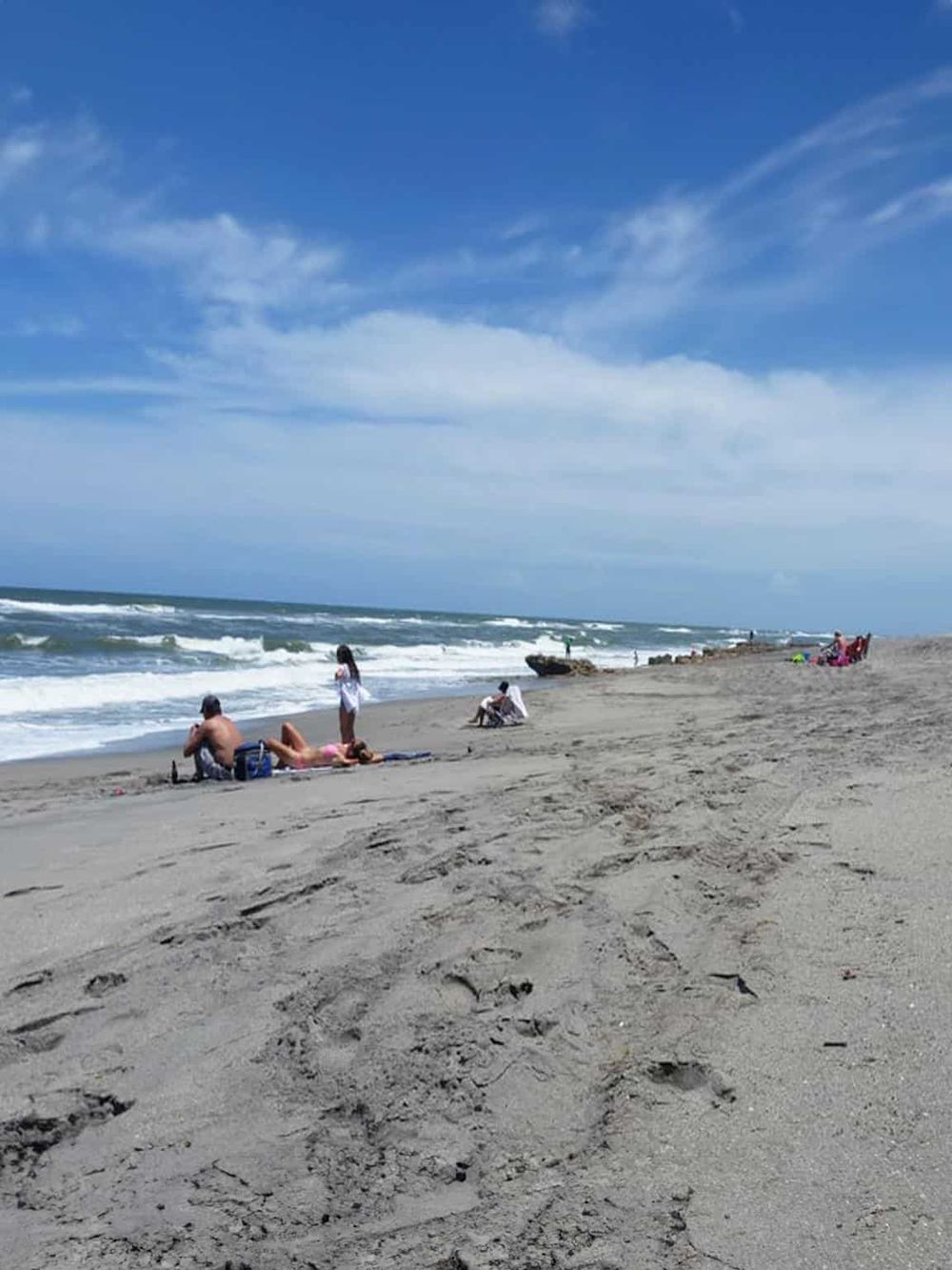 Relaxing beach scene with people enjoying the ocean, sand, and blue sky at QuestForDirections.
