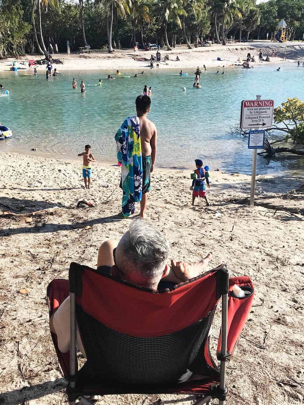 Relaxing beach scene with people swimming, playing, and enjoying warm weather at a tropical seaside location.