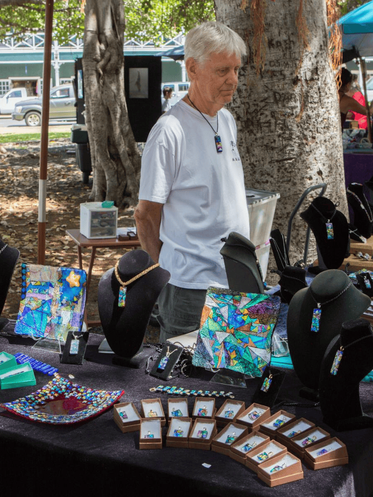 Colorful jewelry display at outdoor market, handcrafted jewelry artisan showcasing unique art pieces.