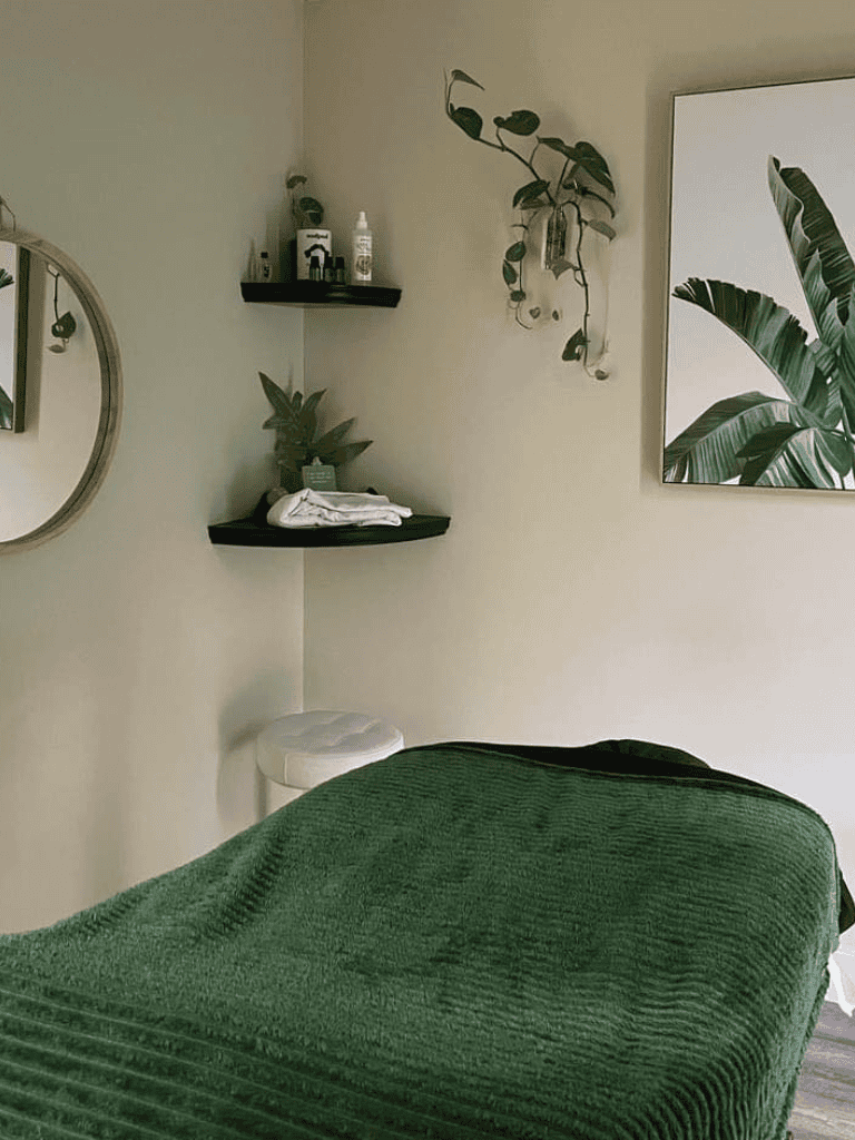 Relaxing massage therapy room with green decor and natural plant elements.