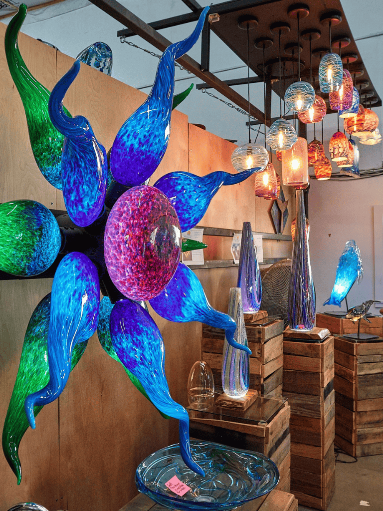 Colorful handcrafted glass art sculptures with decorative lighting in an art gallery.