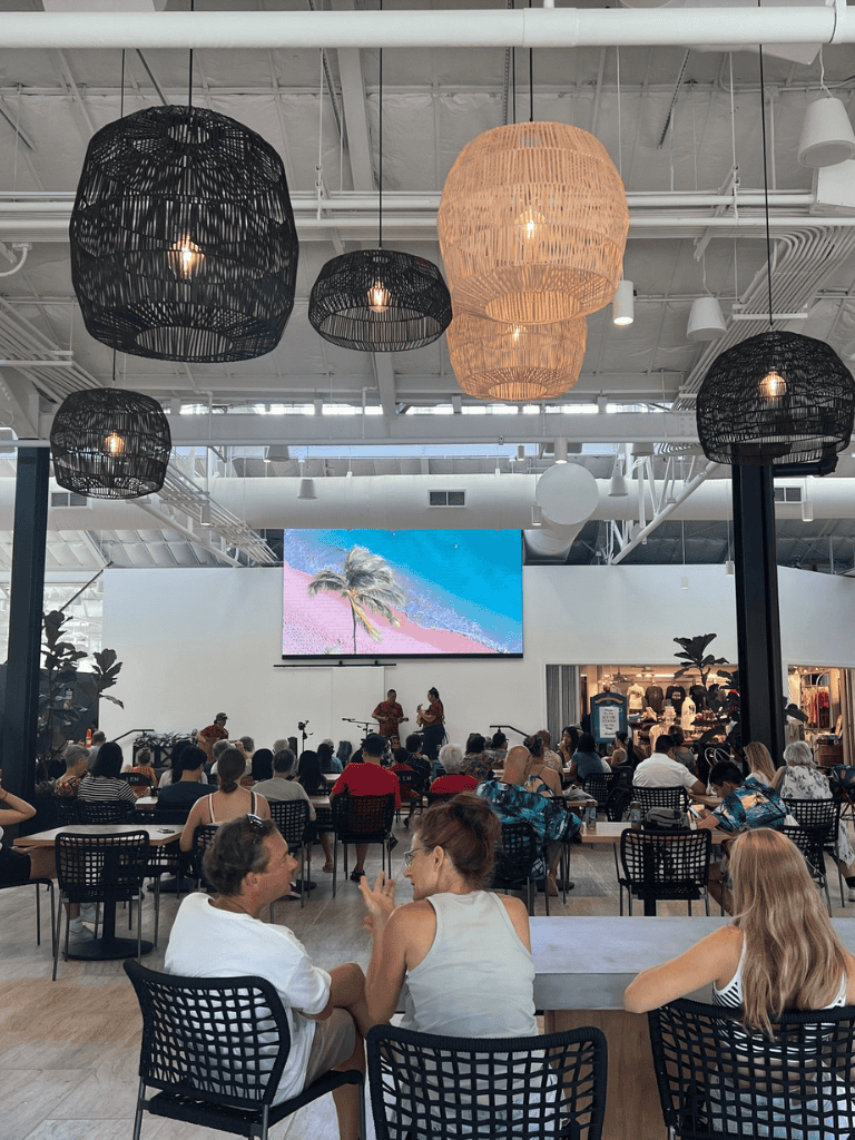 - Modern shopping mall interior with hanging wicker lamps and a large digital screen displaying a beach scene.