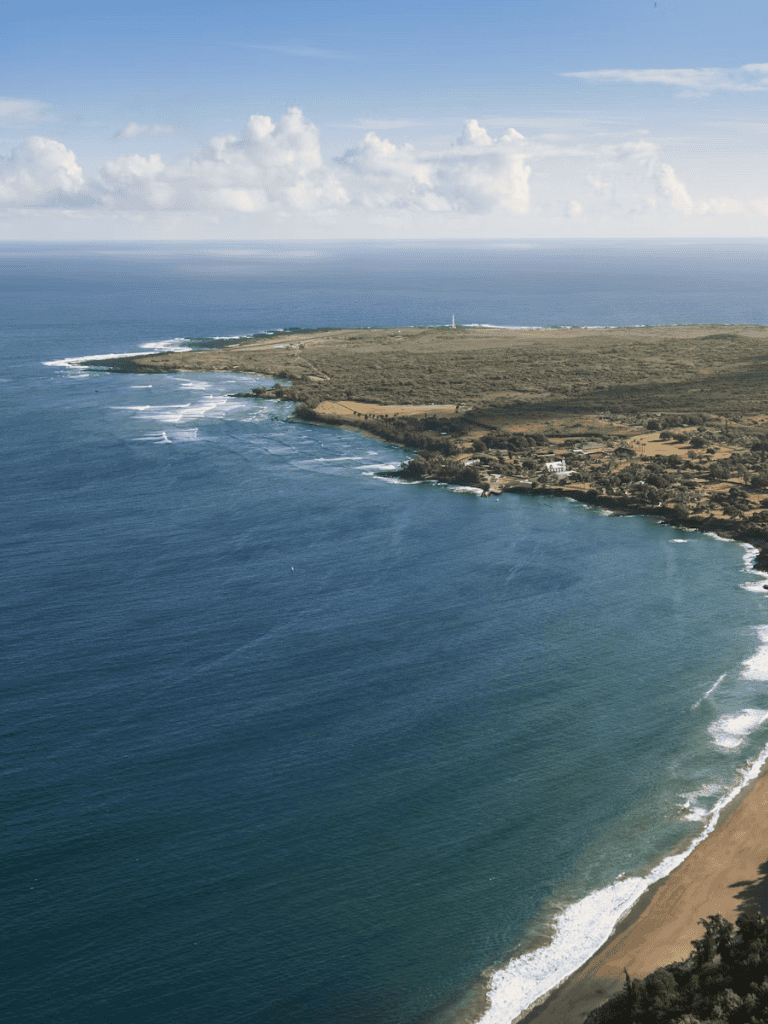 Seaside coastal view with lighthouse, ocean, and sandy beach, illustrating scenic travel destinations.