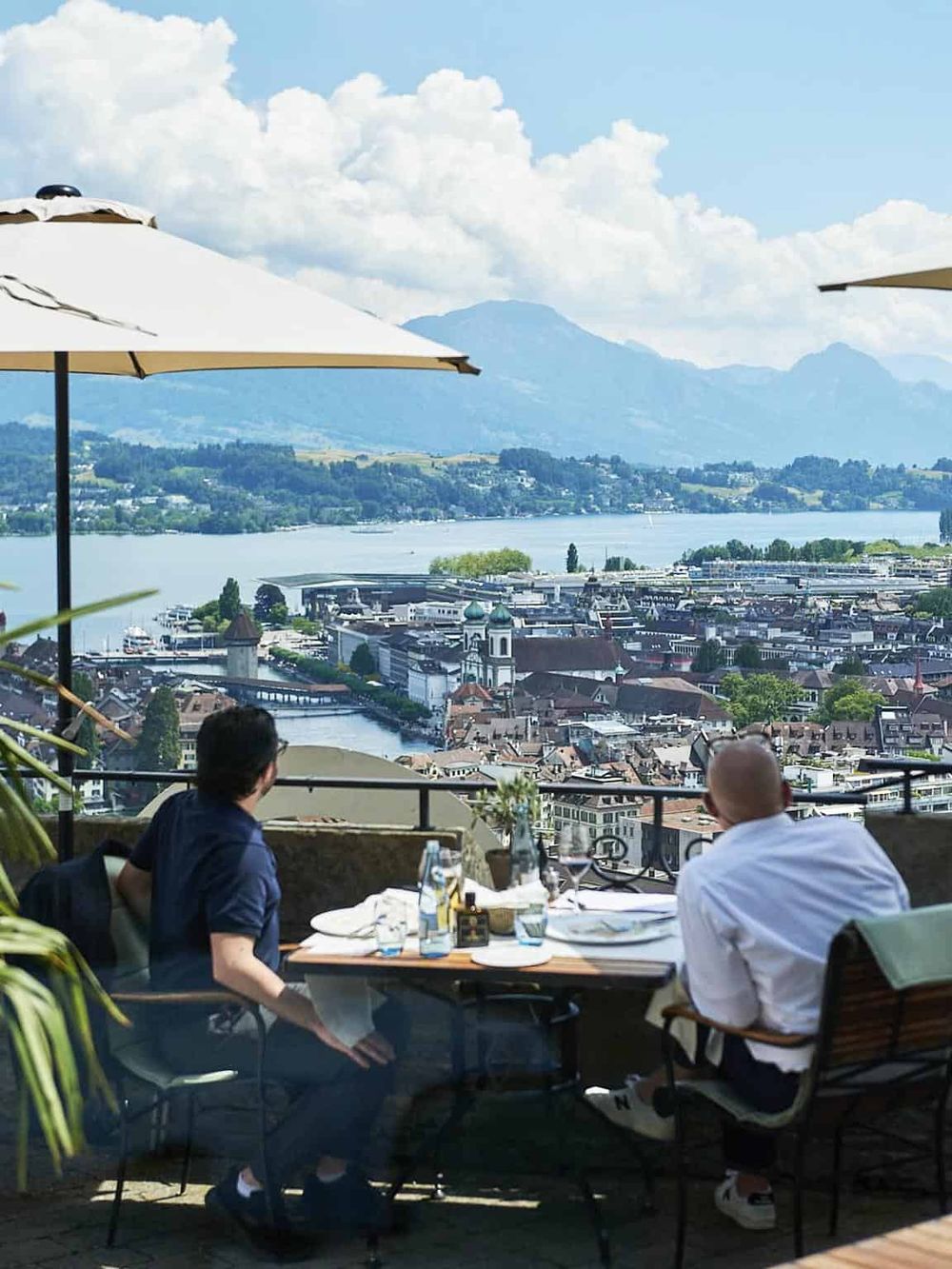 Breathtaking view of a lakeside city skyline from a rooftop restaurant with mountains in the background.