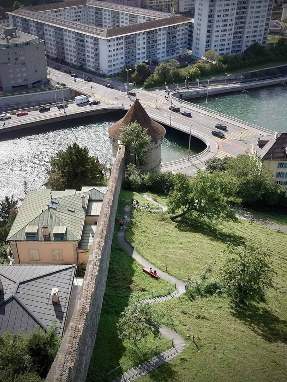 Ancient city wall with tower and scenic park along the river in Zurich, Switzerland.