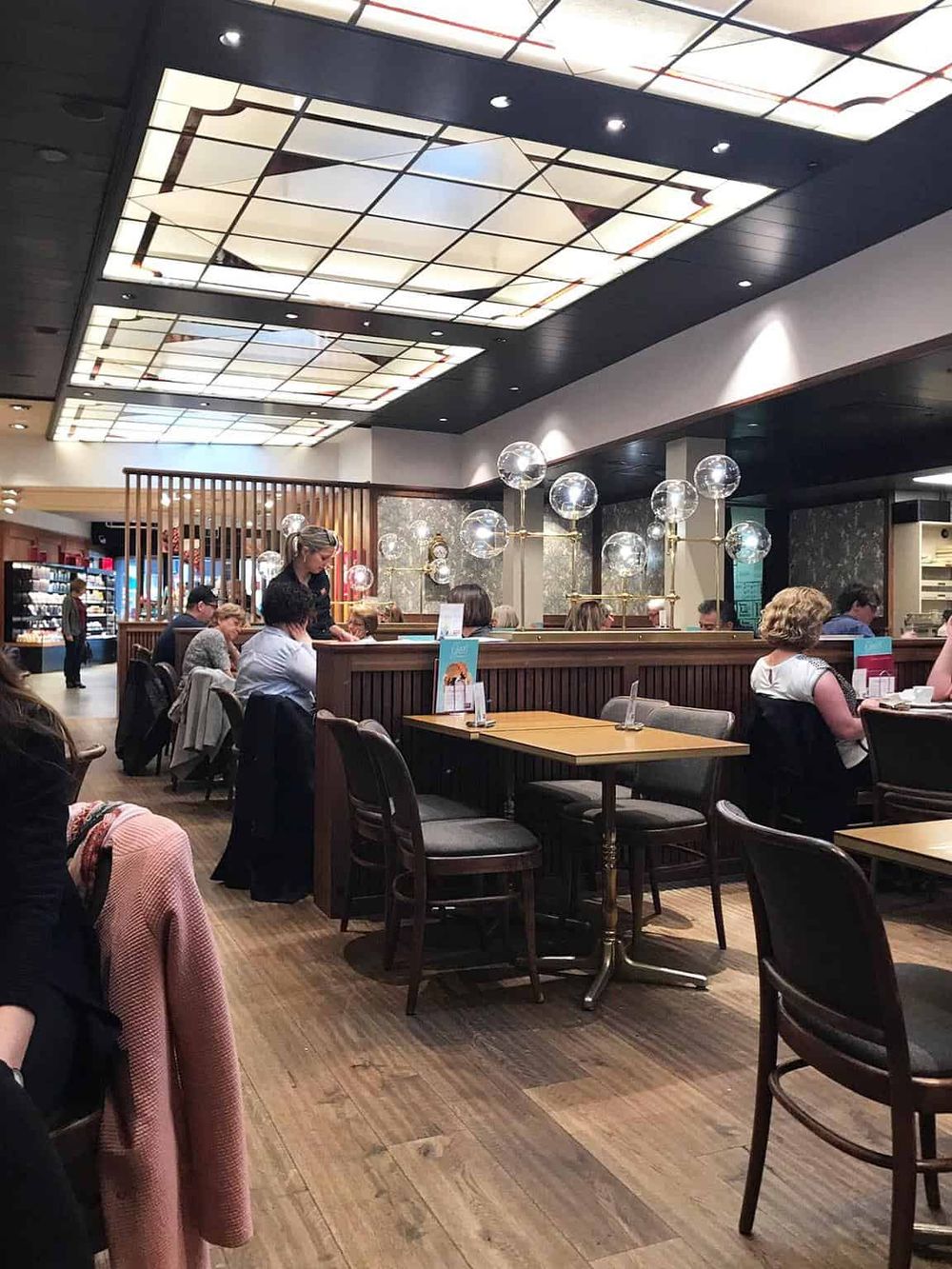 A cozy, modern restaurant interior with warm lighting, wooden accents, and diners enjoying their meals.