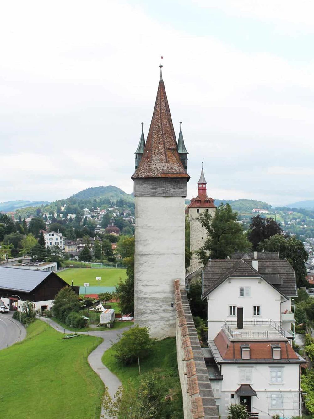 Colorful historic tower with city and green landscape background, travel photography of Swiss architecture.