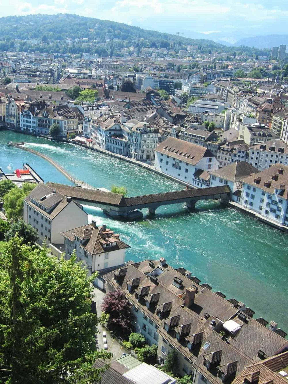 Vivid aerial view of Zurich, Switzerland, showcasing the city's historic architecture along the Limmat River and lush green hills.