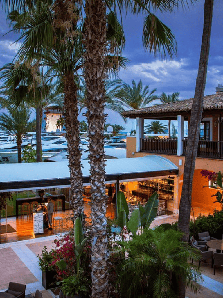 Luxurious beachfront vacation resort with palm trees, pool, and bar, perfect for tropical getaways.