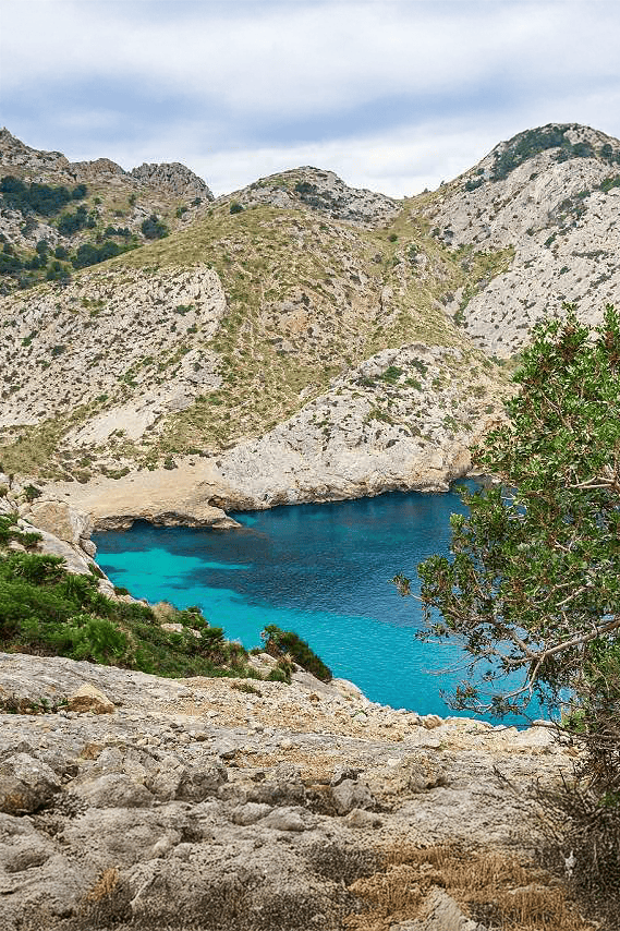 Vibrant blue lake surrounded by mountainous landscape with rocky terrain and sparse vegetation.