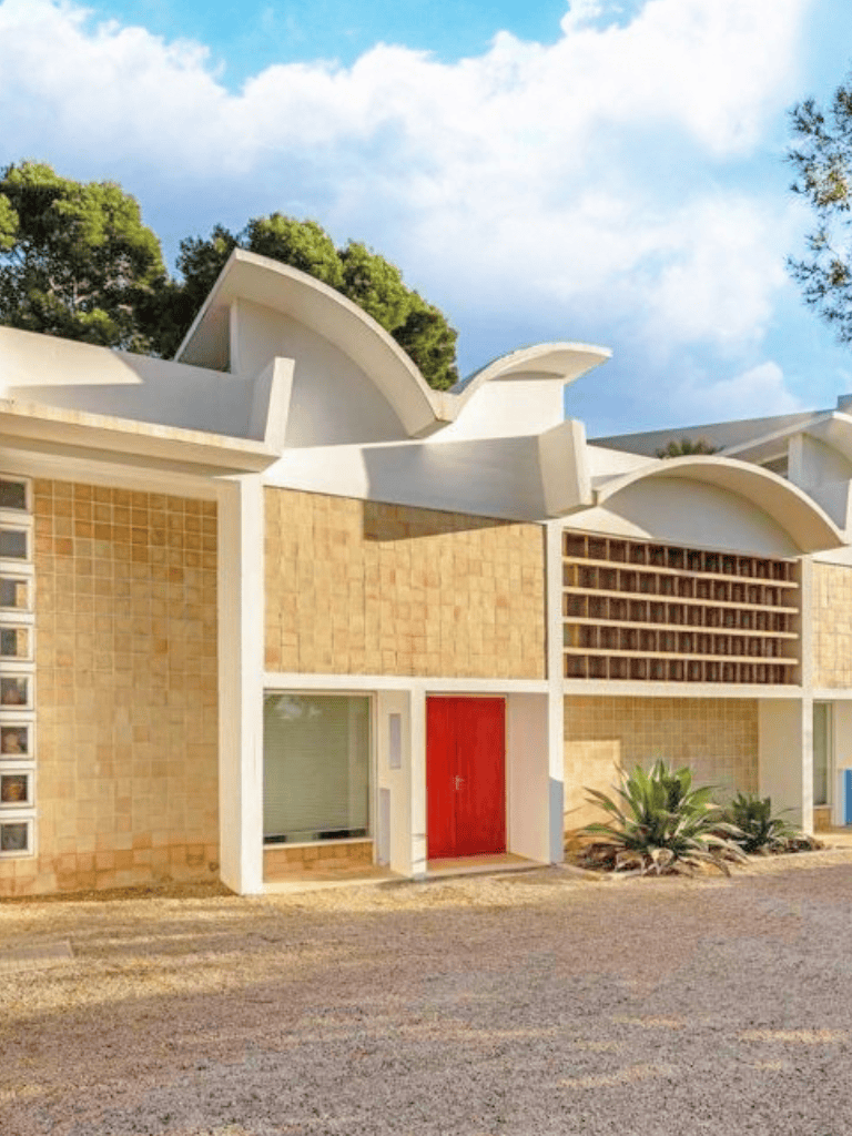 Modern architectural building with unique roof design and vibrant red door, perfect for directions and navigation inquiries.
