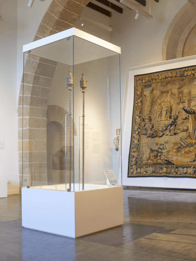 Intricate ceremonial torches displayed in glass case at museum exhibit.