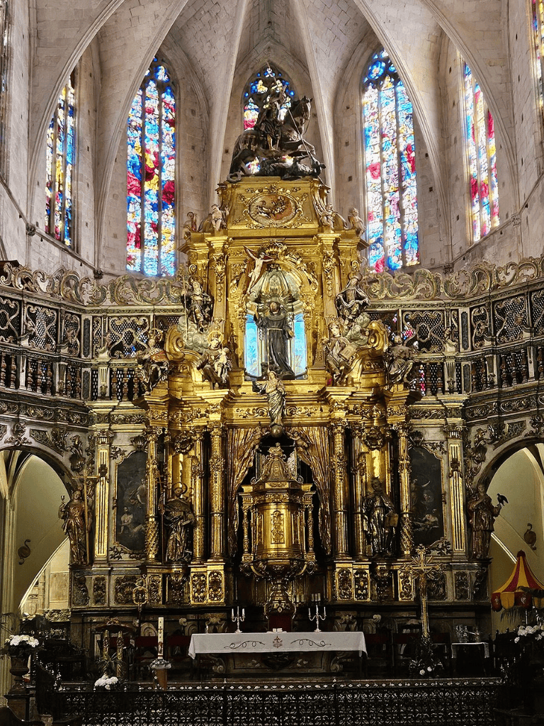 Ornate church altar with gold accents and stained glass windows, showcasing historical religious artwork.