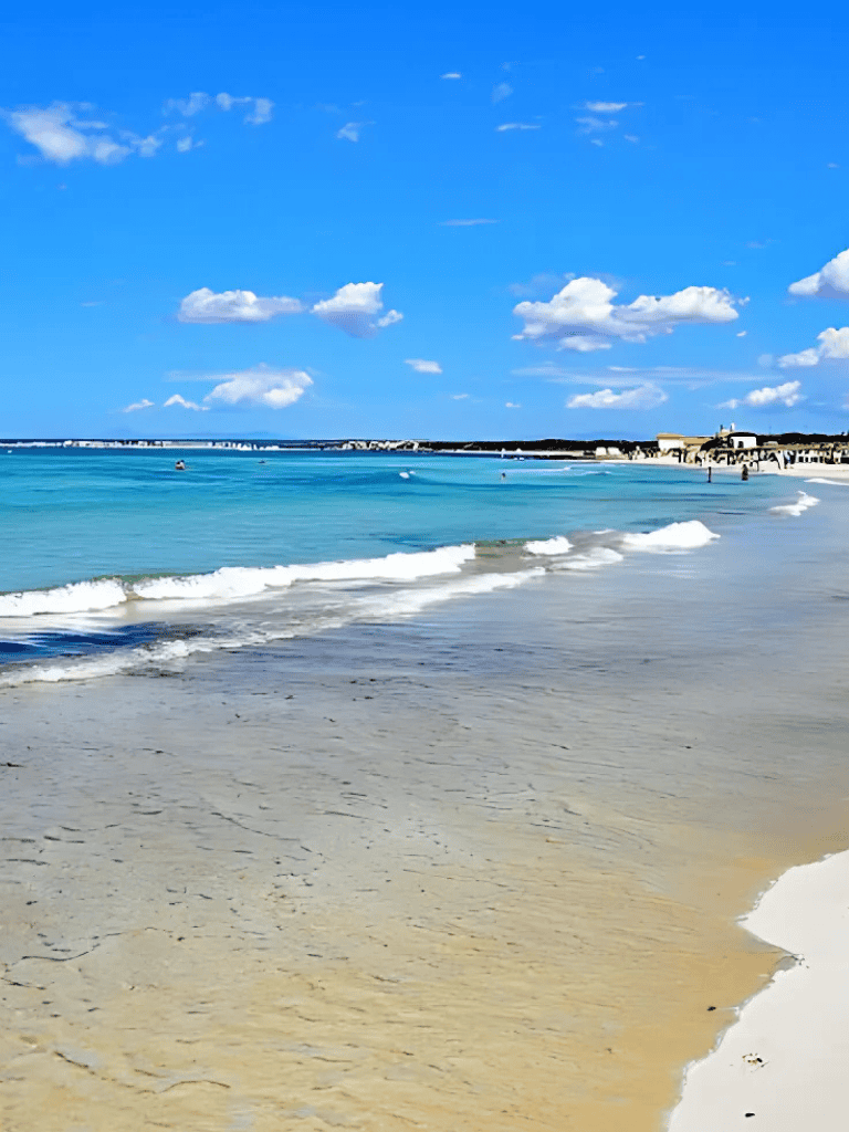 Pristine beach with blue ocean and white clouds, perfect for travel and seaside relaxation.
