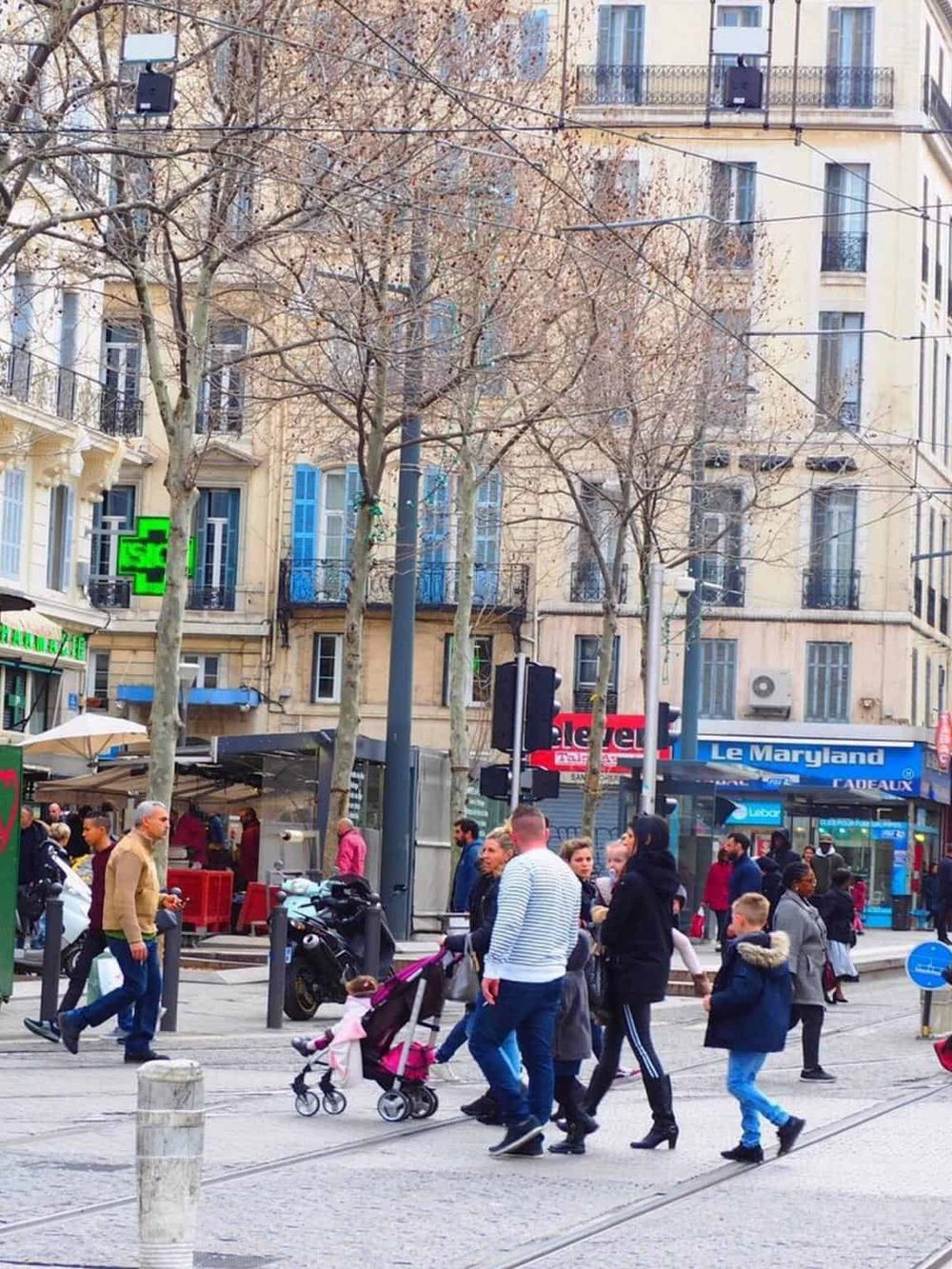 Busy city street crossing in Paris with pedestrians, shops, and historic buildings for urban directions.