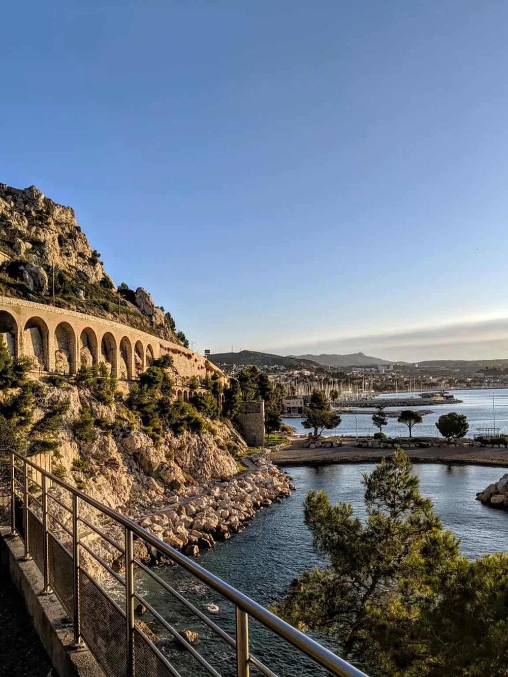 Vibrant coastal landscape with a mountain tunnel, marina, and serene waters, perfect for travel and navigation insights.