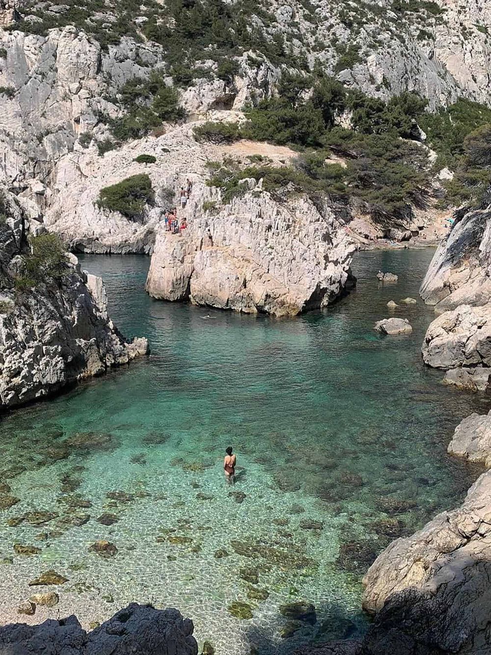 Serene rocky cove with crystal-clear water and natural cliffs.