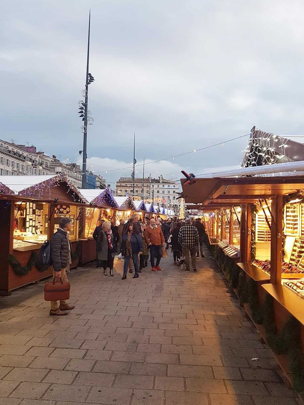 Colorful Christmas market in a city square with wooden stalls and festive decorations, ideal for holiday shopping and holiday cheer.