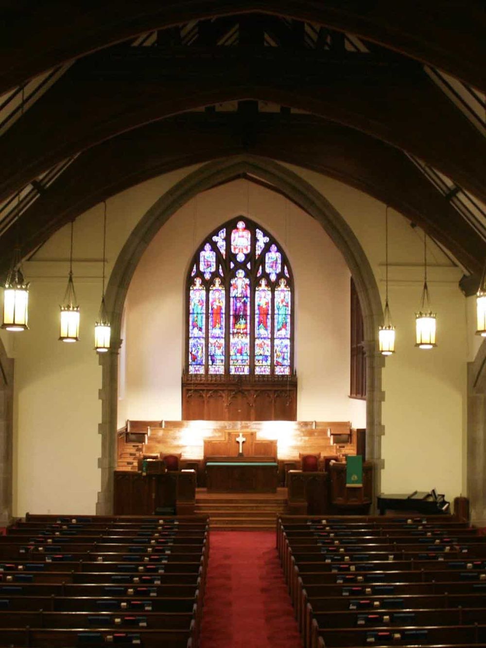 Vibrant stained glass church window inside a historic chapel or cathedral with wooden pews.