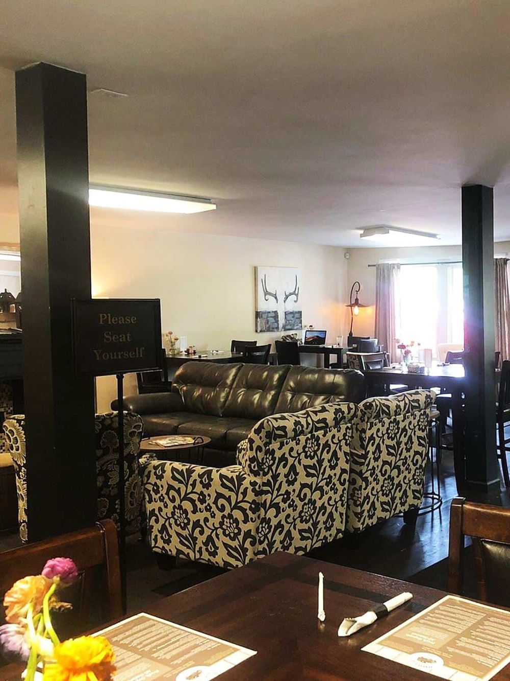 Cozy restaurant interior with black and floral patterned seating, ambient lighting, and a welcoming atmosphere.