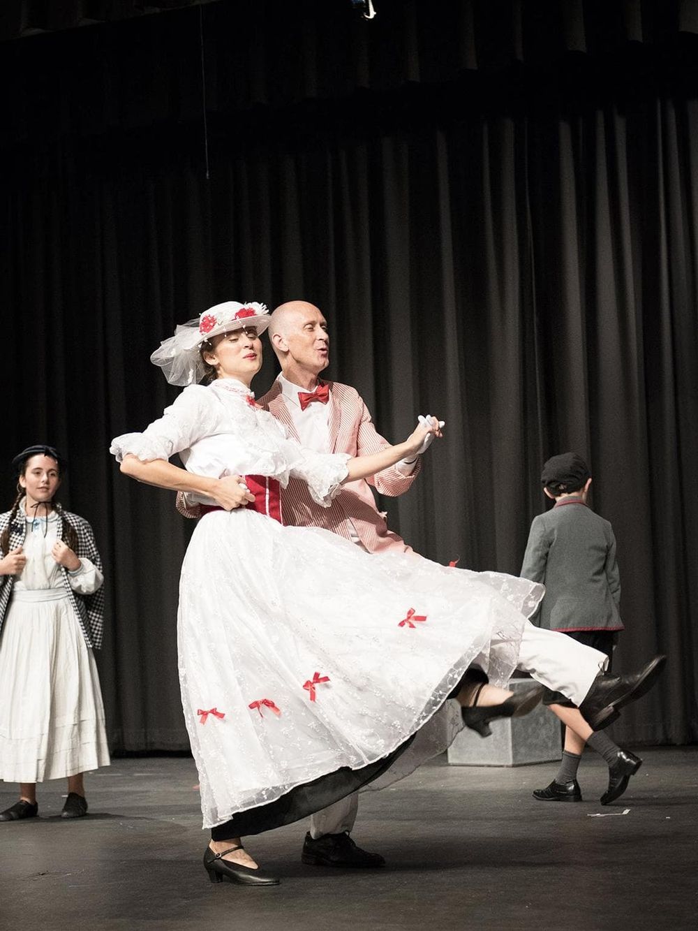 Charming theatrical performance of a couple dancing in vintage costumes on stage.
