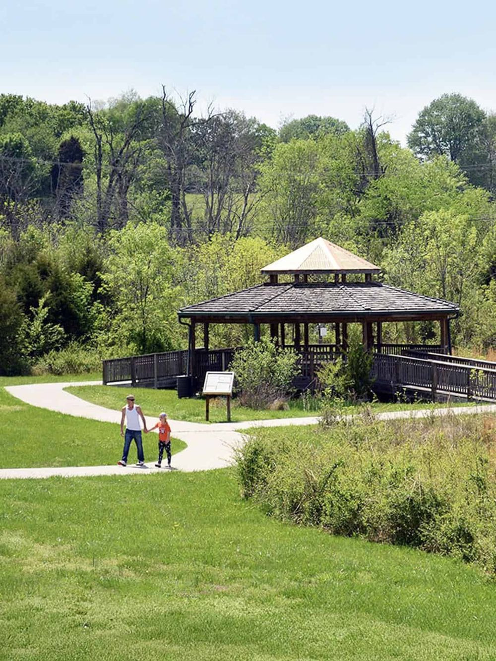 Woodland park with walking trail and family enjoying nature, outdoor recreation, scenic views, and park amenities.