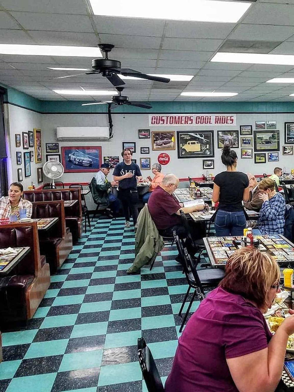 Vibrant retro diner interior with classic automotive decor and customers enjoying their meals.