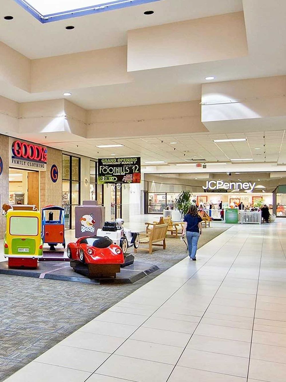 Bright indoor shopping mall featuring children's rides, benches, and retail stores like JCPenney and Goody's.