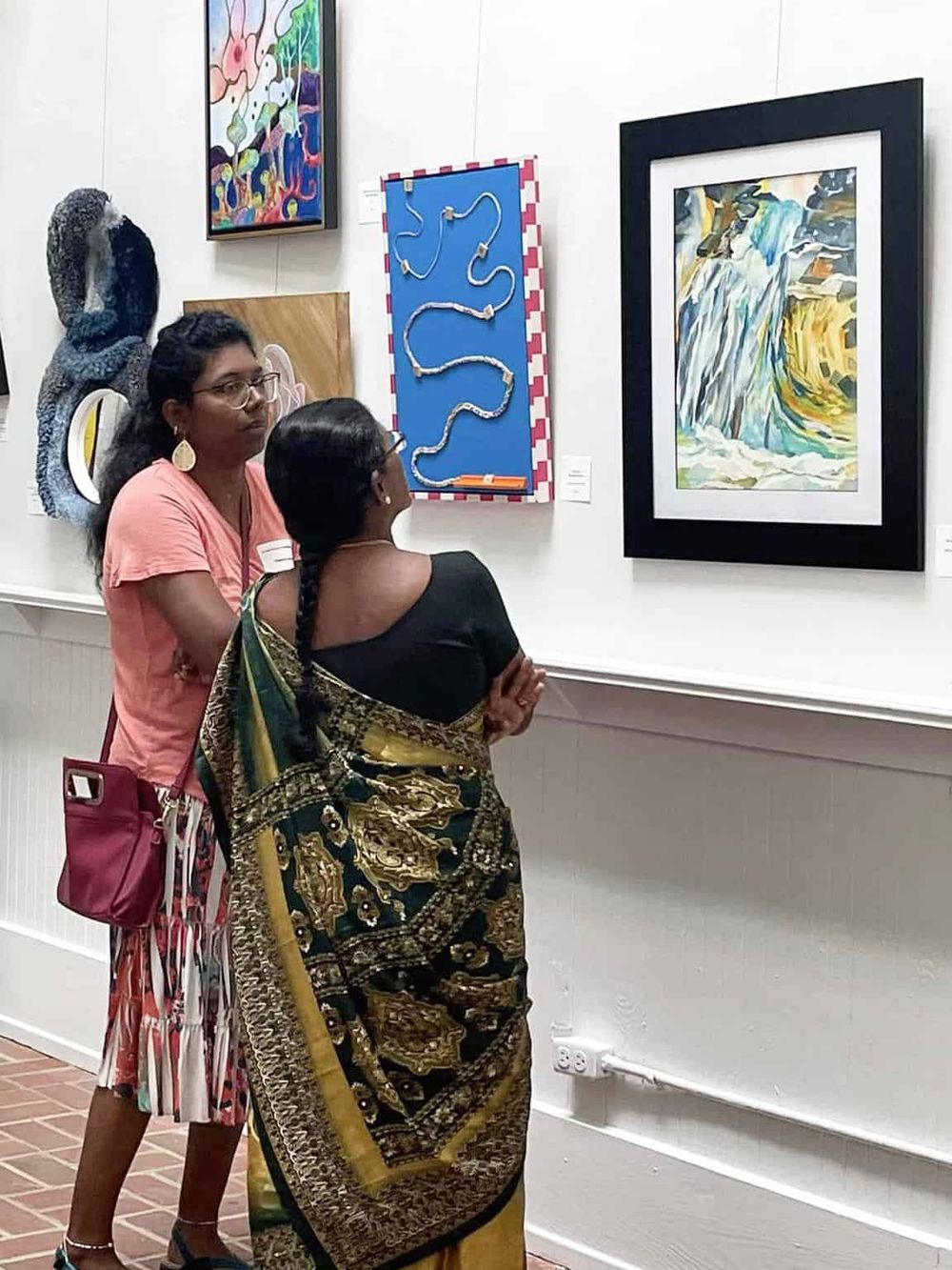 Colorful art gallery with diverse paintings and visitors appreciating artwork.