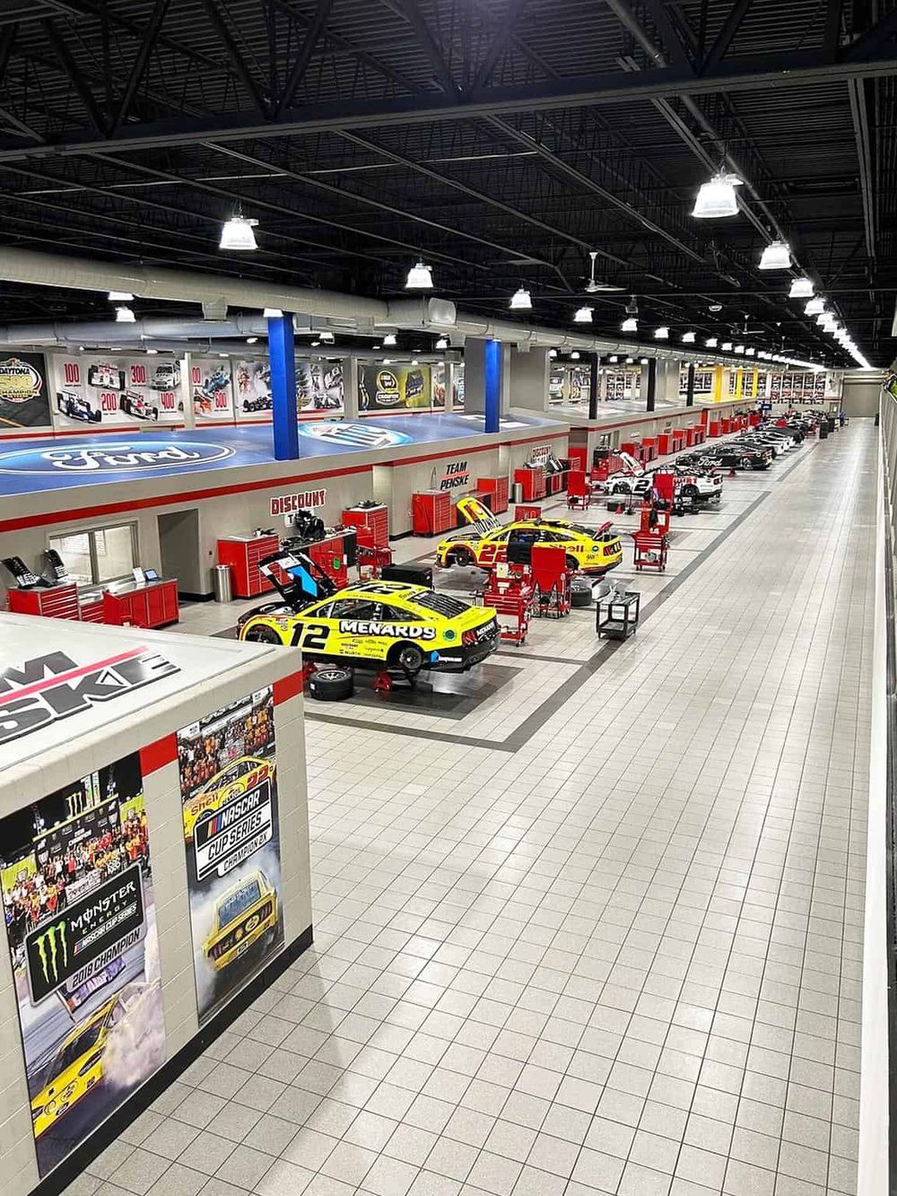 High-tech race car service center with multiple race cars, tools, and memorabilia, perfect for motorsport enthusiasts and automotive project needs.